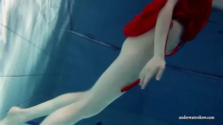 Блондинка в красном платье на голое тело ныряет в бассейне